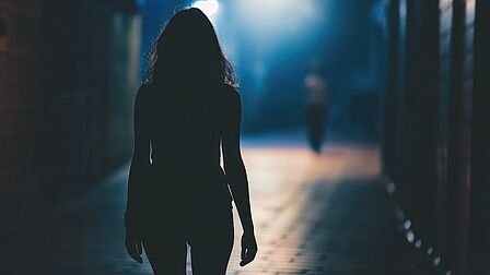 Vrouw loopt alleen in het donker over straat