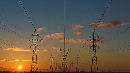 Verschillende elektriciteitsmasten met zonsondergang.