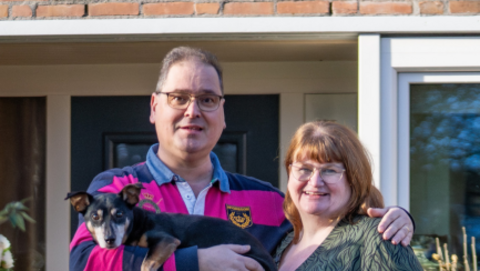 Henk en Mieke staan met hun hondje Spencer voor hun woning in Heerhugowaard